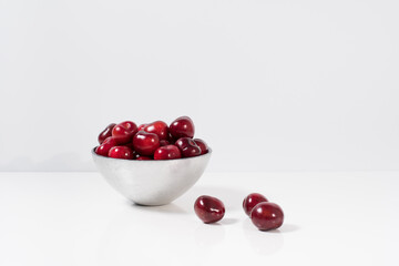Cerezas dulces en un recipiente de plata y fondo blanco	