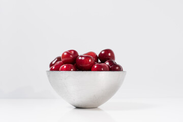 Cerezas dulces en un recipiente de plata y fondo blanco	