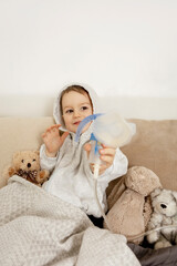 Sick little boy with inhaler for cough treatment. Unwell kid doing inhalation on his bed. Flu...