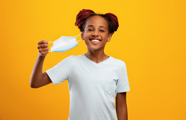 Cheerful black girl taking off face mask