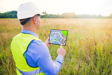 Architect using digital tablet with blueprints and surveying a new residential housing building land plot - 480393159