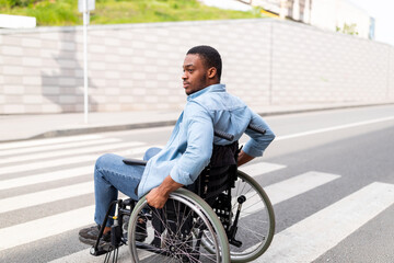 Quality of life and impairment. Millennial paraplegic black man in wheelchair using crosswalk...