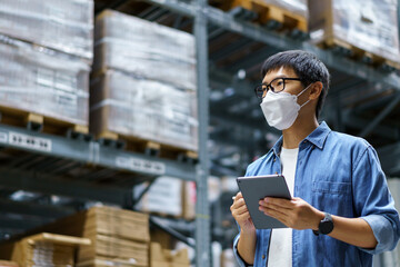 Fototapeta na wymiar New Normal Asian men, staff, product wearing face mask. counting Warehouse Control Manager Standing, counting and inspecting products in the warehouse