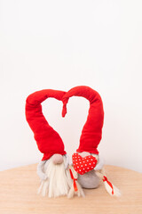 Two gnomes in love in red caps with a heart shape on a white background vertical format