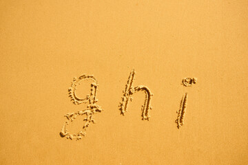 alphabet letters g h i handwritten in sand