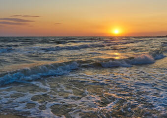 Soft sea waves and bubbles on the beach with sunset sky