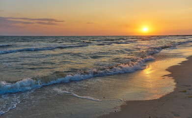 Soft sea waves and bubbles on the beach with sunset sky