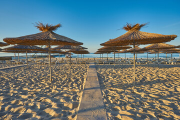 Thatched beach umbrellas and loungers on a beach at an idyllic tropical resort