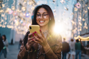 Cheerful millennial blogger enjoying mobile networking during travel vacations for visiting new...