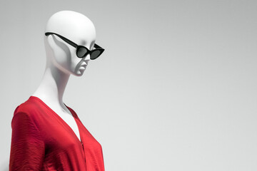 Female mannequin portrait in sunglasses and red dress. Sale and advertising theme. Copyspace for text