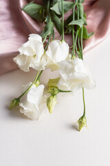 White eustoma and pearl necklace. Twig of eustoma on silk background. Terry variety 