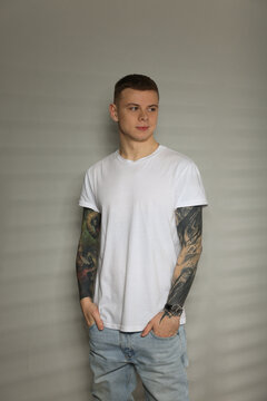 Young man with tattoos near light wall