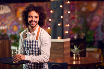 Portrait Of Smiling Male Server Clearing Table In Cool Bar Or Club © Monkey Business