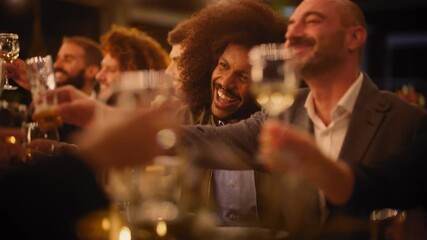 Big Dinner Party with a Small Crowd of Multiethnic Diverse Friends Celebrating at a Restaurant. Beautiful Happy Hosts Propose a Toast and Raise Wine Glasses while Sitting at a Table in the Evening.