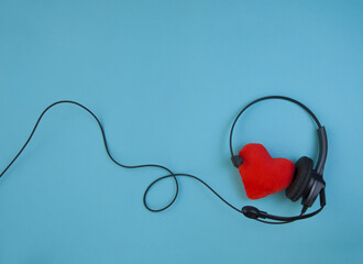 earphone with microphone and heart model on a blue background, top view