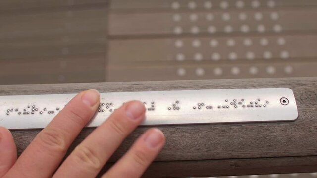 Hand touches the description in Braille. Typhlo pedagogue takes into account the blind and visually impaired people to read, instills in them self-service skills, the ability to navigate in space.