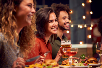 Multi-Cultural Group Of Friends Enjoying Night Out Eating Meal And Drinking In Restaurant Together