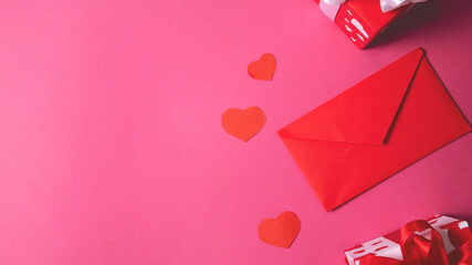 Flat gift box with white ribbon bow, red envelope on pink background. Valentines day celebration,