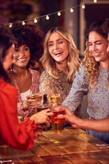 Multi-Cultural Group Of Friends Enjoying Night Out Drinking In Bar Together Making A Toast