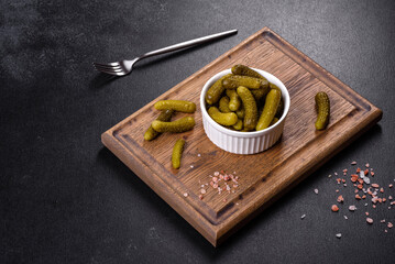 Beautiful pickled cucumbers of small size on a dark concrete background
