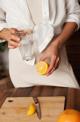 woman making lemon water in the kitchen at home - healthy eating and lifestyle