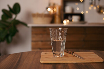 Glass of water on the wooden kitchen table at home. Water balance and healthy lifestyle. 