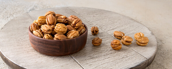 bowl with pecans on wooden table - obrazy, fototapety, plakaty