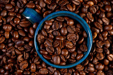 Coffee cup with roasted beans immersed in coffee beans.