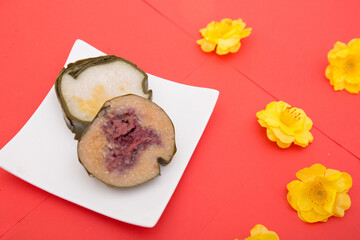 Vietnamese Tet holiday traditional sticky rice cake  and yellow flowers on red background. Lunar...