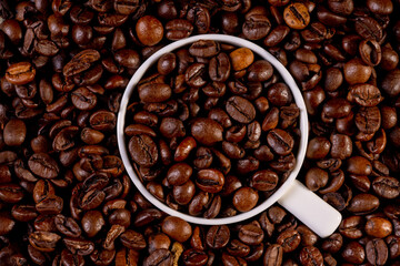 Coffee cup with roasted beans immersed in coffee beans.