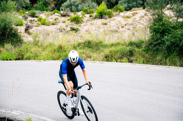 Unrecognizable cyclist climbing a mountain road slope with effort