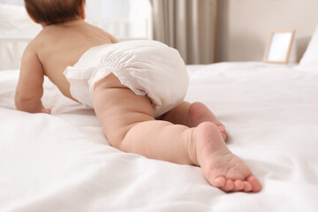 Little baby in diaper on bed at home, back view