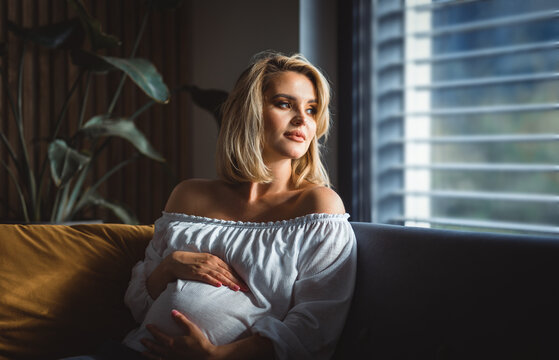 Dreamy portrait of pregnant woman resting at home and thinking about newborn child
