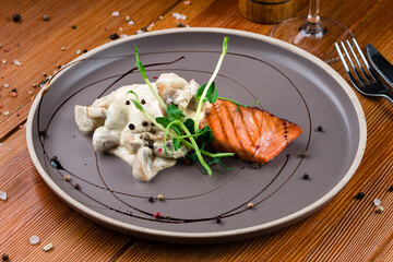 Organic baked salmon fillet topped with creamy mushrooms close-up on a plate
