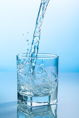 splash of water in a transparent glass on a blue background