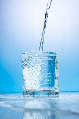 splash of water in a transparent glass on a blue background