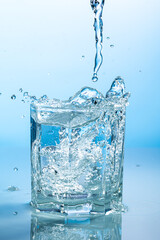 splash of water in a transparent glass on a blue background