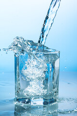 splash of water in a transparent glass on a blue background