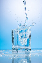 splash of water in a transparent glass on a blue background