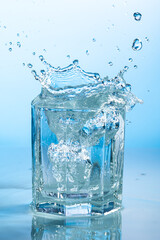 splash of water in a transparent glass on a blue background