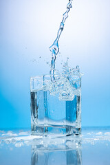 splash of water in a transparent glass on a blue background