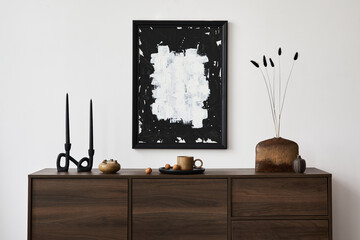 Creative composition of modern living room interior design with mock up poster frame, brown commode, vases, candlestick and personal accessories. White wall. Copy space. Template.