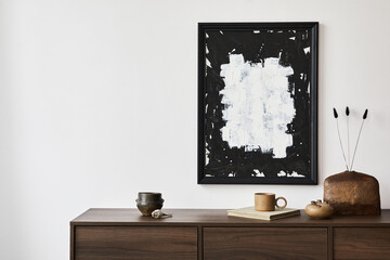 Creative composition of modern living room interior design with mock up poster frame, brown commode, vases and personal accessories. White wall. Copy space. Template..