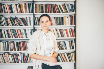 Young woman standing in front of bookshelves. Education concept.