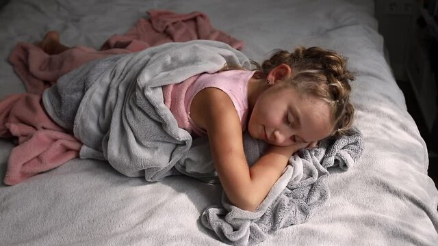 Close up of little girl sleeping in bed in light room. Preschool girl getting out of bed. Good morning calm awakening 4k