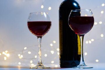 Two transparent empty glasses, a bottle of wine and a bokeh from the lights. The eve of a romantic dinner. A postcard for holidays and dinners.
