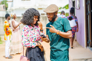 excited african guy and a lady with smart phone- outdoor communication concept