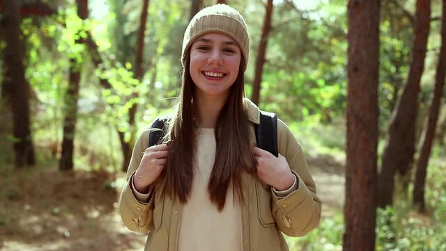 Teenage American girl young woman hiking with backpack in forest woodland. Video portrait of hiking teenager girl. Sport healthy concept.