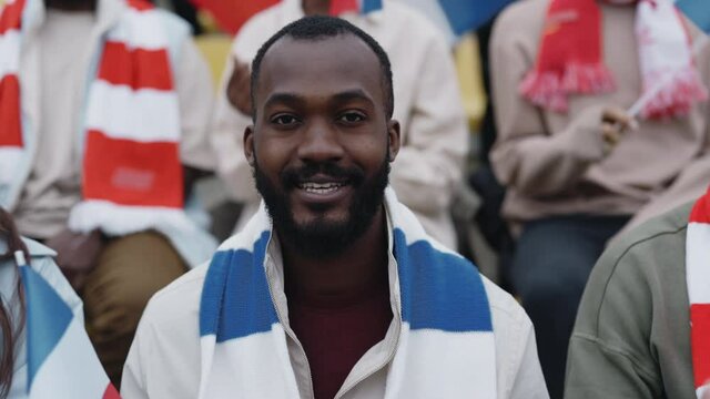 African american soccer fan with french scarf watching game