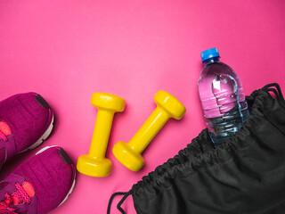 Two heavy dumbbells, training shoes and plastic bottle of water in a black bag. Workout equipment...